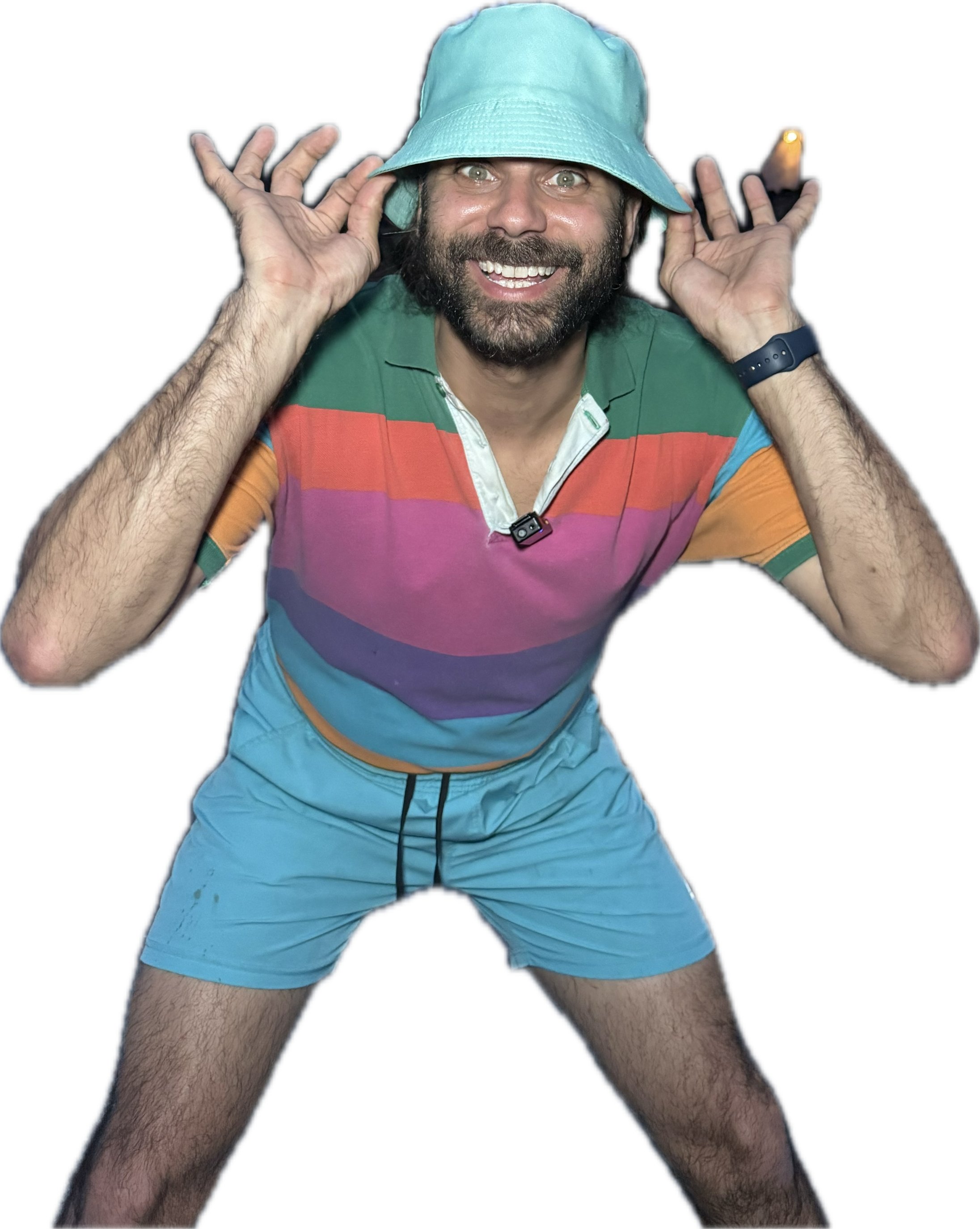 A man wearing a wide-brimmed light blue hat smiling and holding the hat with both hands. He is dressed in a colorful striped polo shirt and shorts, with a camera clipped to his collar. The background is black, highlighting the man and his colorful attire.