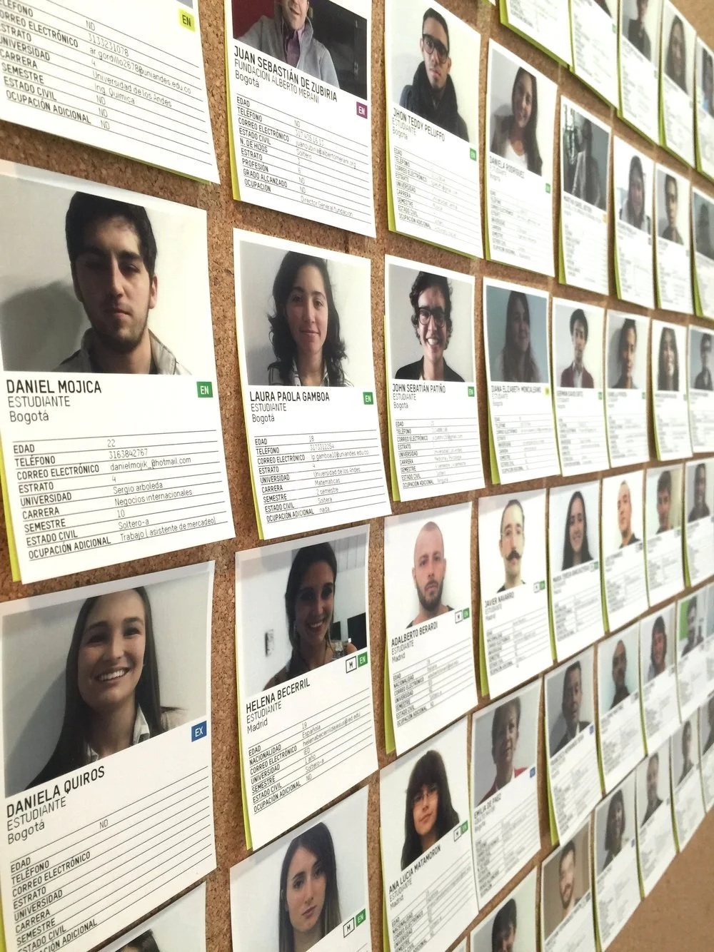 A bulletin board displaying multiple rows of student ID photos and information cards, featuring students' portraits, names, ages, contact details, universities, careers, semester, civil status, and occupation details.