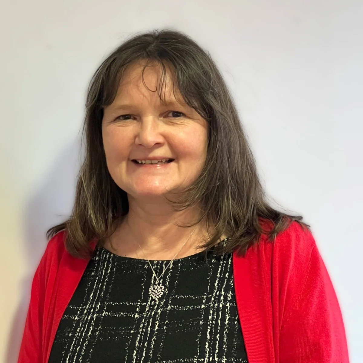 Headshot of Kids Inspire trustee, deborah smiling standing against a white wall.