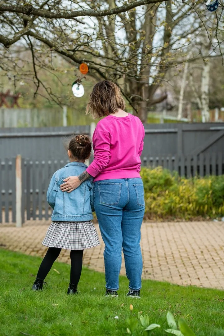 woman and child facing away looking at a tree. womans hand on childs shoulder