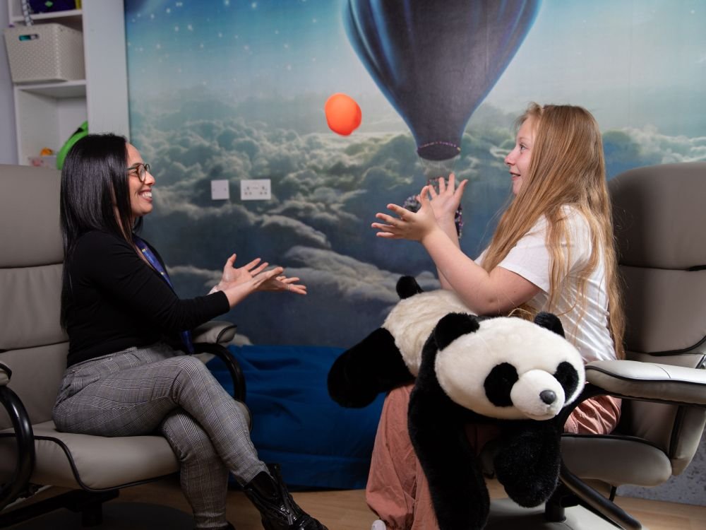 Therapist and child smiling as they throw a sensory toy to each other during a play therapy session.