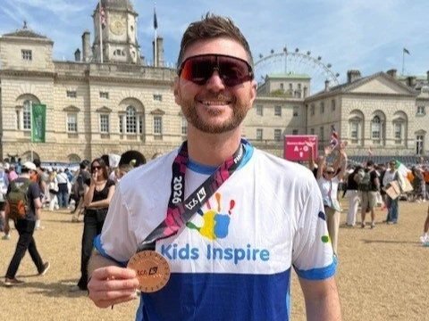 A man with a London Marathon medal and a Kids Inspire running top
