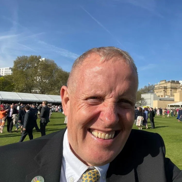 Volunteer mentor Martyn taking a selife smiling with lots of people in the background.