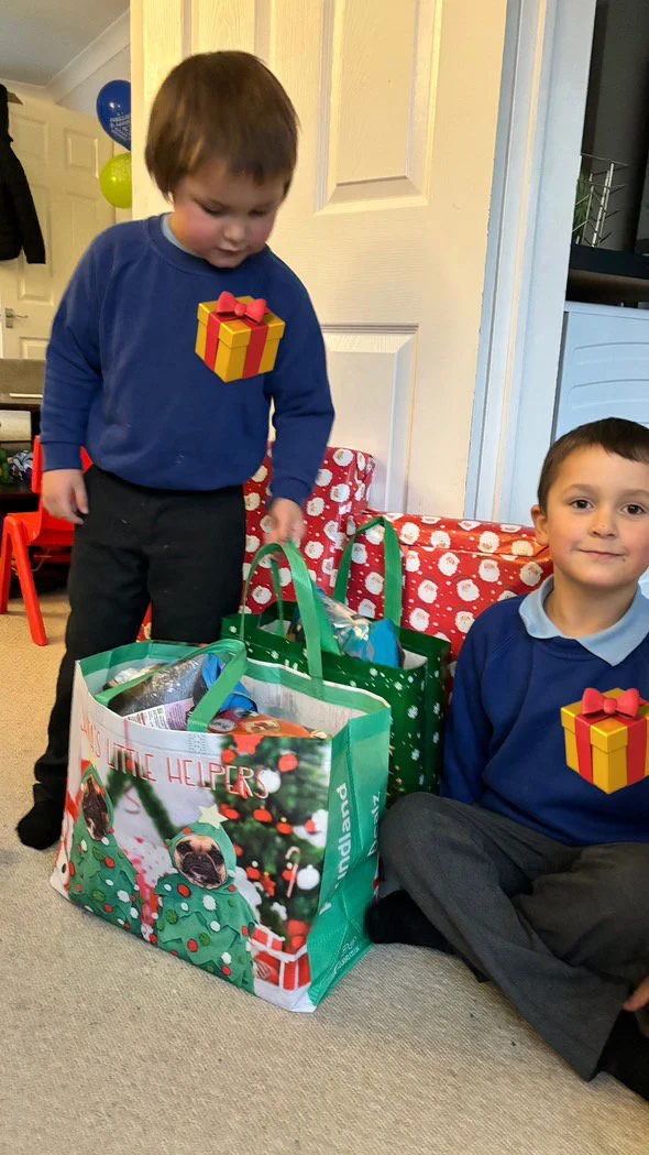 Two young boys, of primary achool age, sat down on the floor surrounded by bags of Christmas gifts from the Christmas Appeal