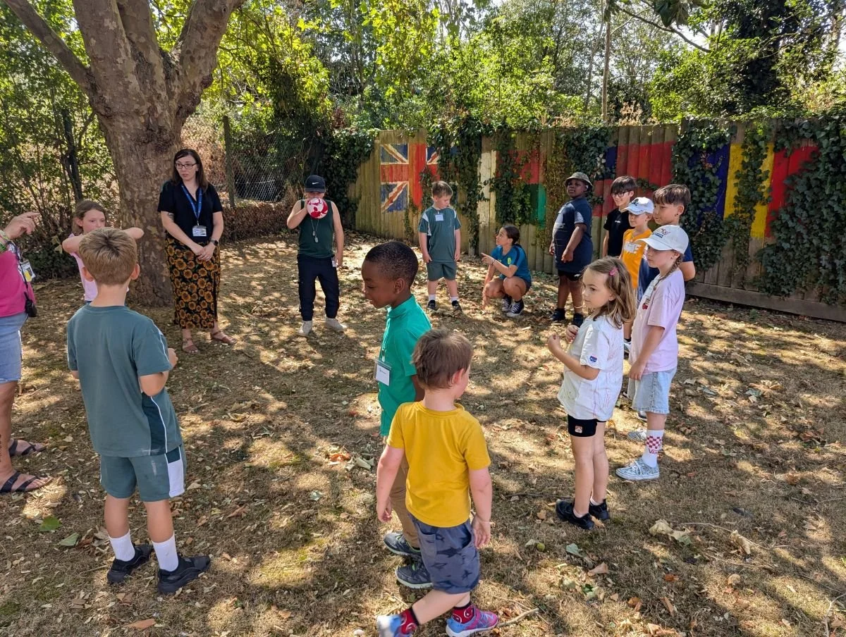 Children gathered around playing an activity outside at Kids inspire Holiday Club