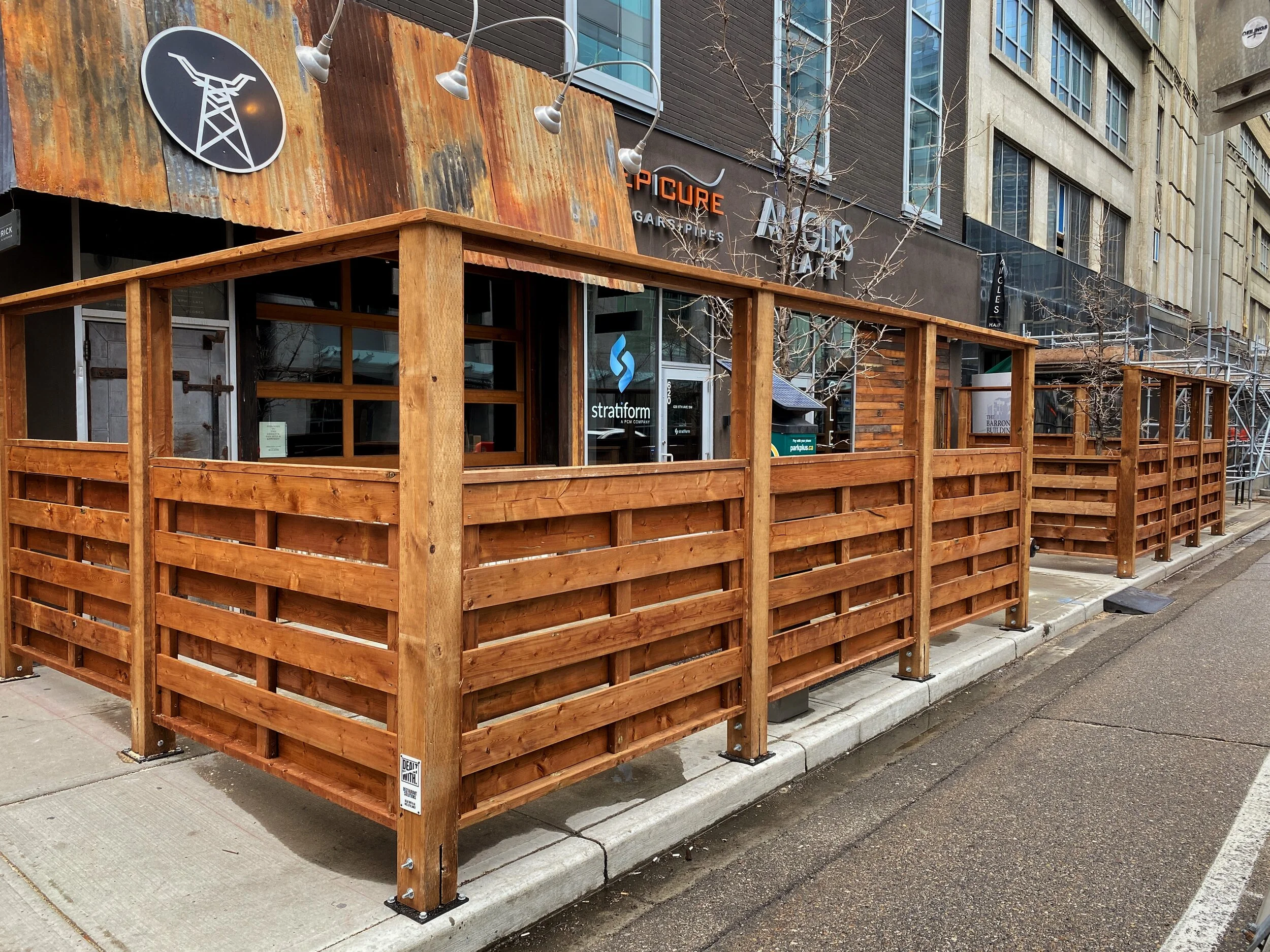 Wooden outdoor dining area with fence outside a restaurant