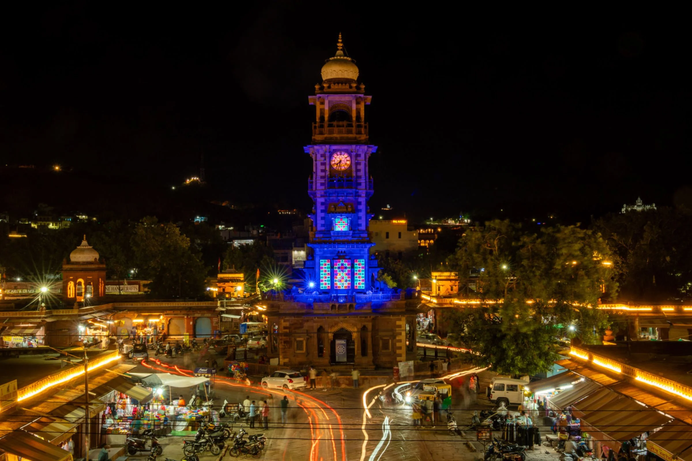 Night view of shemza.digital #17 glowing under ultraviolet light at the Clock Tower in Sardar Market, Jodhpur, India.