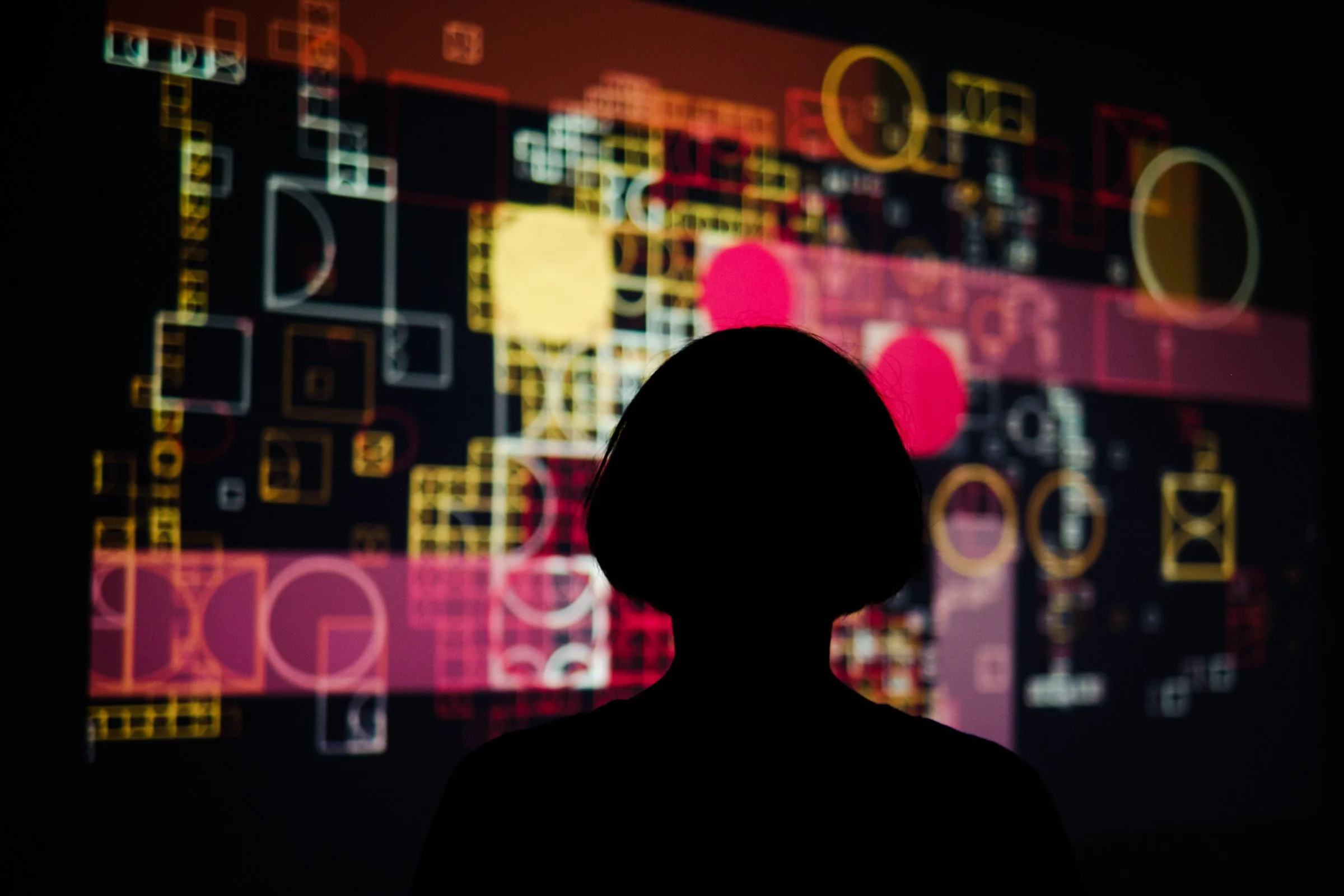 Silhouetted visitor standing in front of the evolving geometric projection in shemza.digital #3.