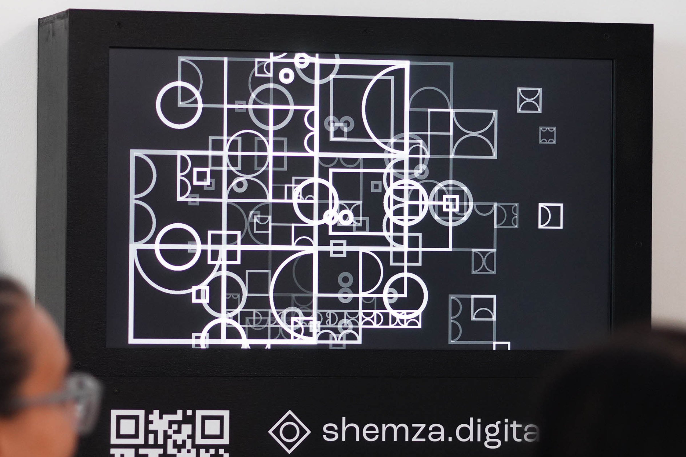 Close-up of shemza.digital #3 displayed on a wall-mounted screen showing the evolving geometric digital artwork.