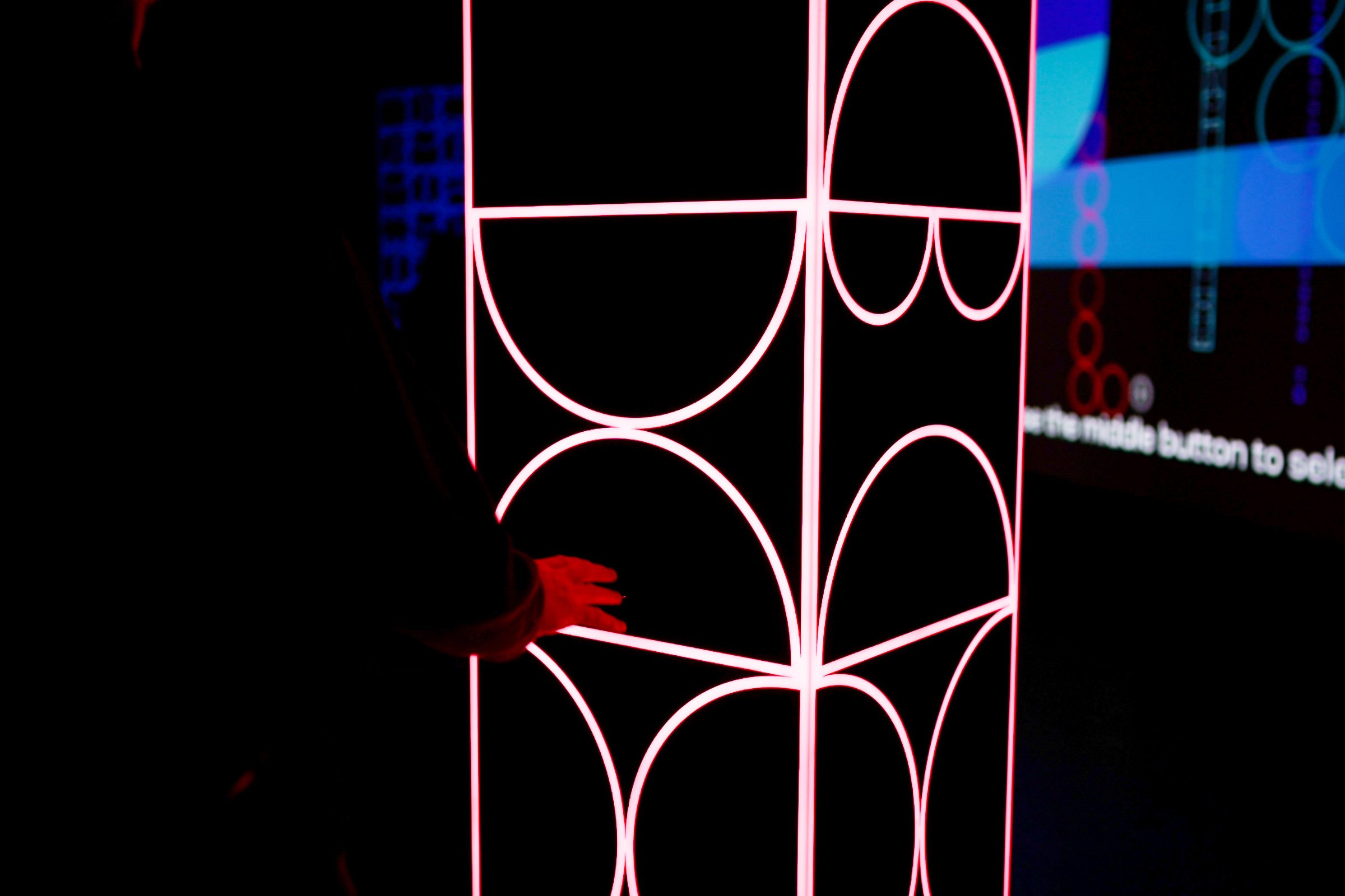Visitor interacting with shemza.digital #6, activating the sculpture's red illumination through movement.