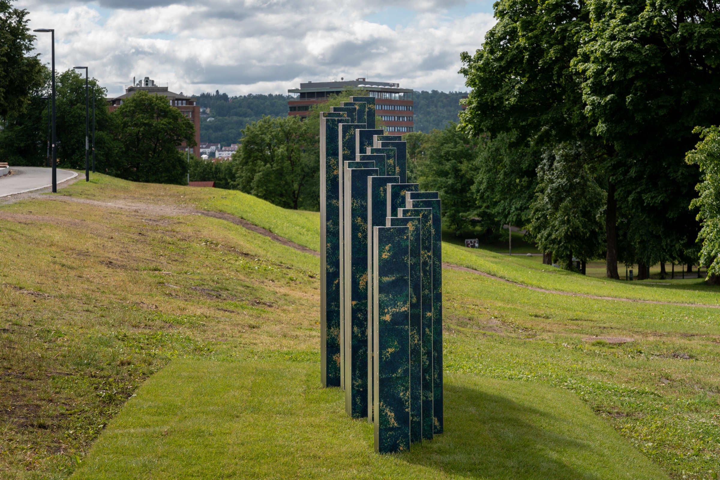 Full view of Ocean Rise, a large wave-shaped public sculpture installed among the trees in Tøyen Park, Oslo.