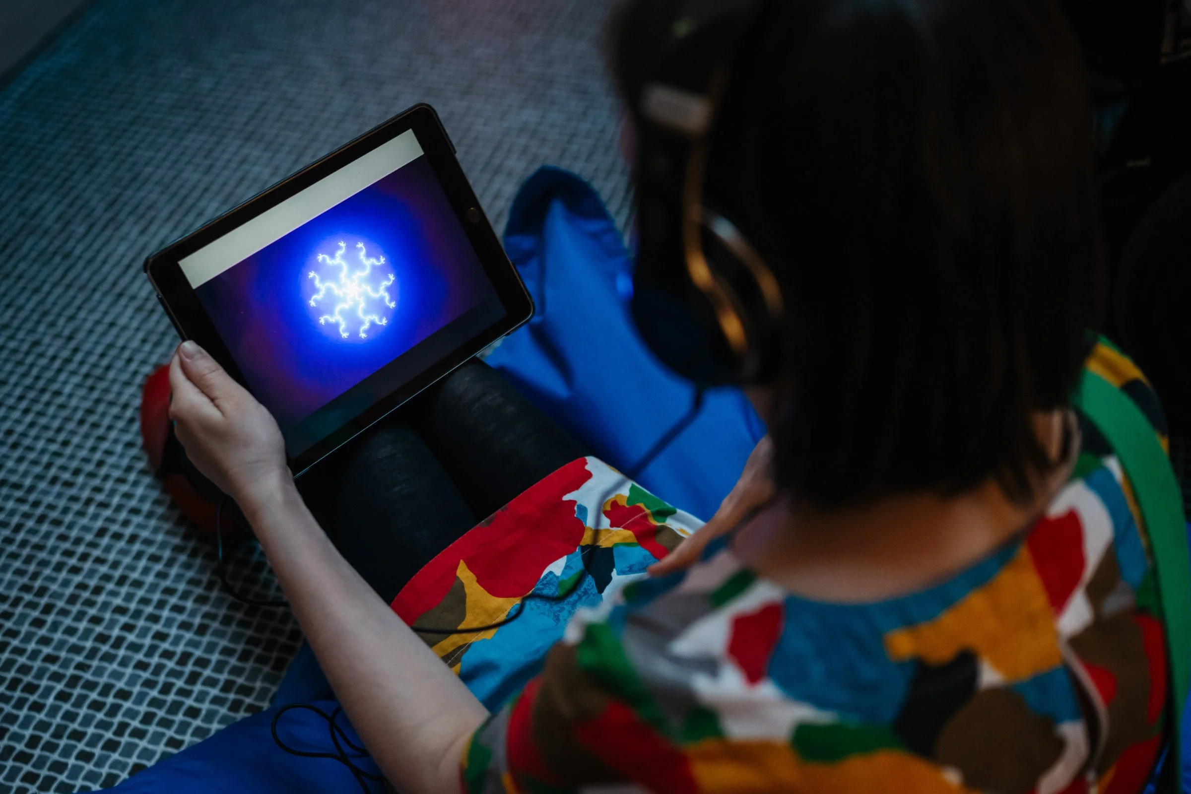 Visitor experiencing shemza.digital roots #1 on an iPad with headphones during the immersive audiovisual meditation artwork.