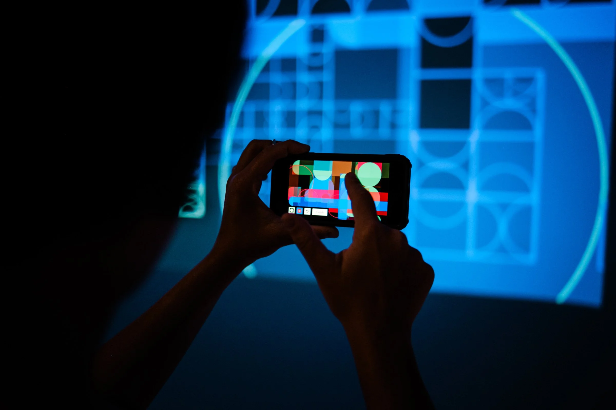 Close-up of a visitor creating a geometric digital painting on their mobile phone for shemza.digital #3.