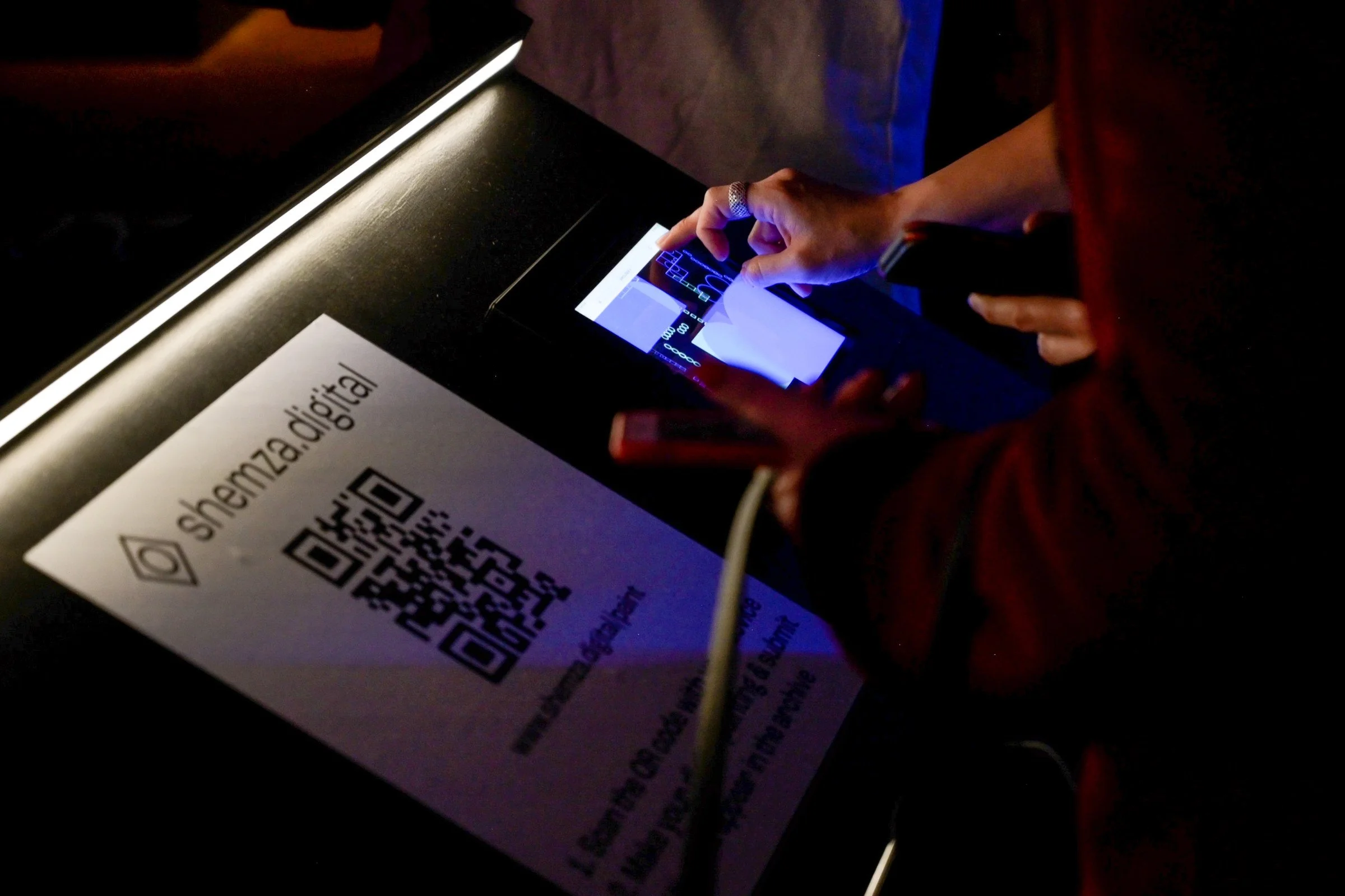Visitors using an iPad to create digital paintings for shemza.digital #8, with their artworks appearing immediately in the live gallery projection.