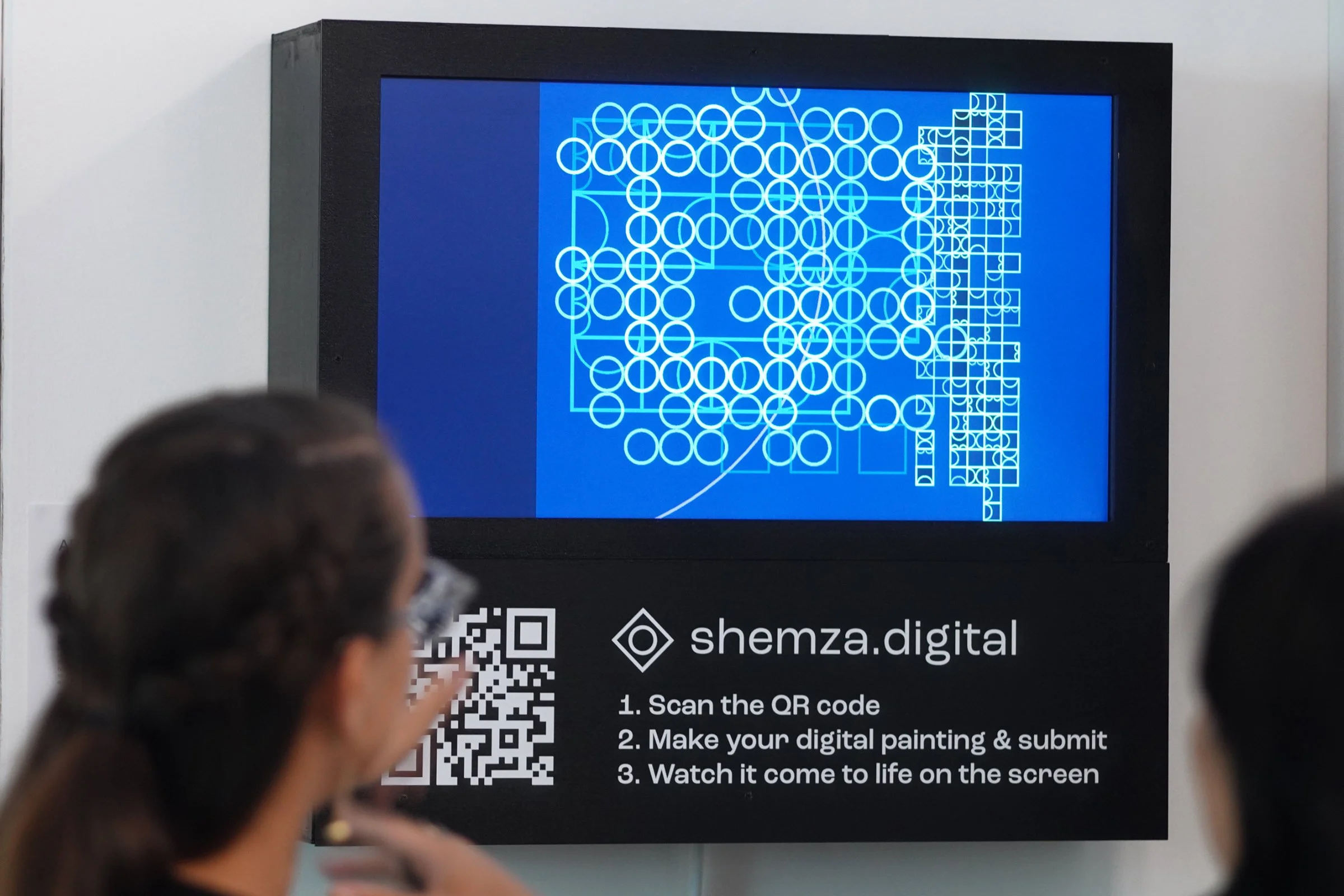 Gallery view of shemza.digital #3 displayed on a digital screen with visitors engaging with the artwork.