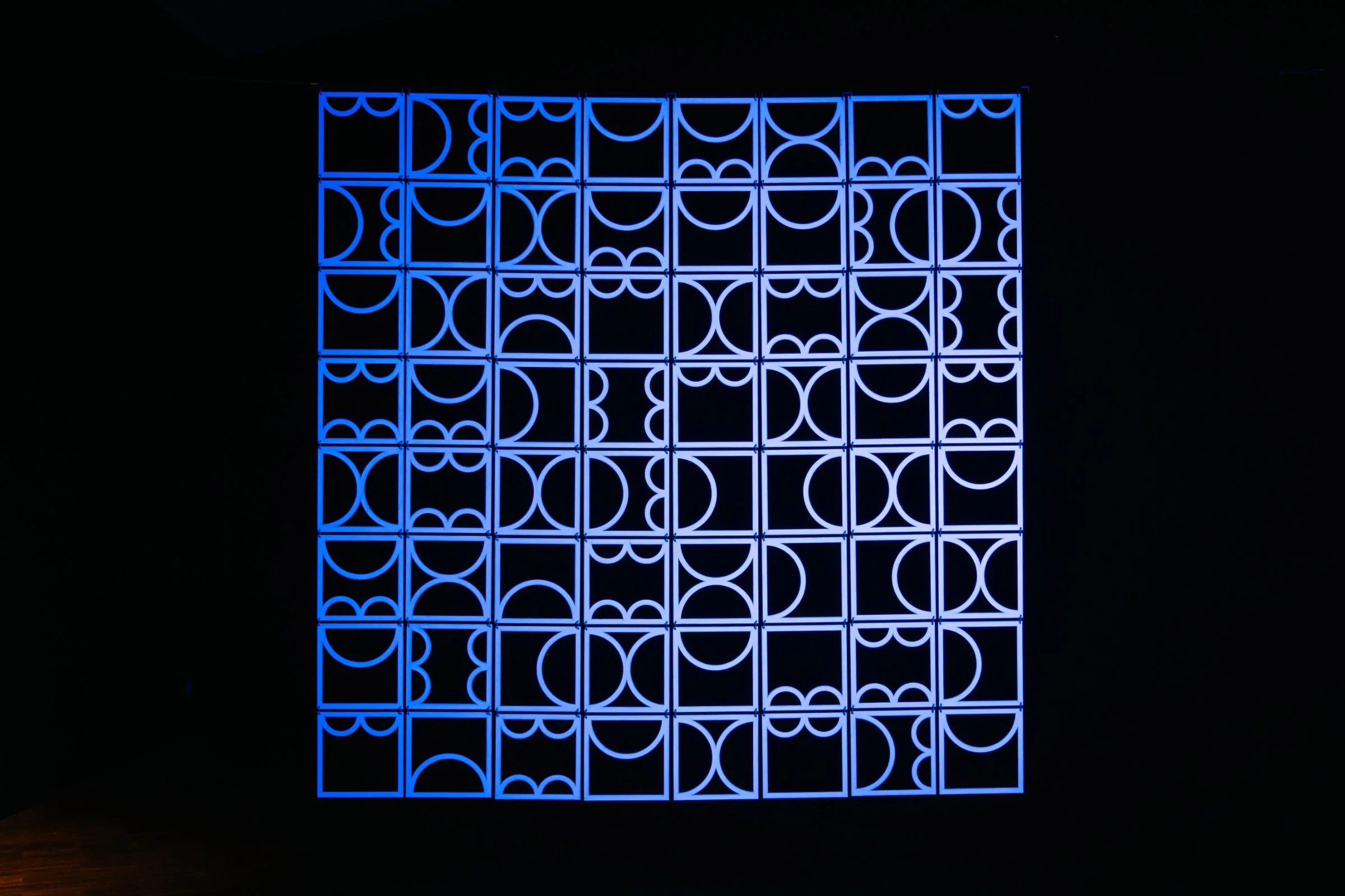 Close view of the glowing white geometric forms in shemza.digital #9, inspired by Anwar Jalal Shemza’s City Walls series and traditional jali screens.