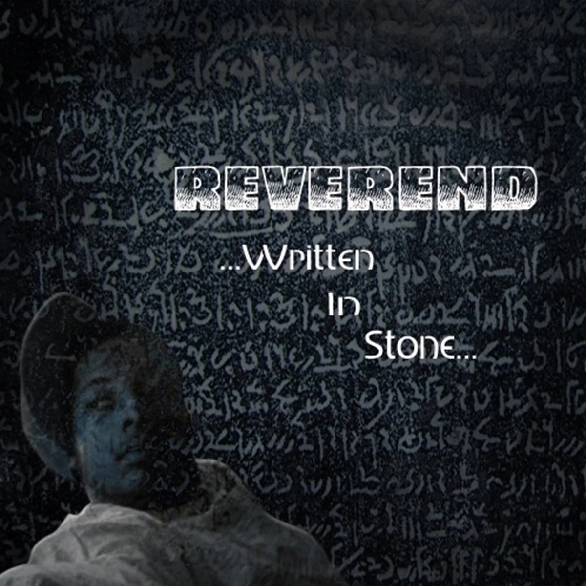 [Image Description: A man wearing a hat facing left sits in front of a blue image of multi-lingual text on a stone tablet. The words "Reverend Written in Stone" are written in white.]