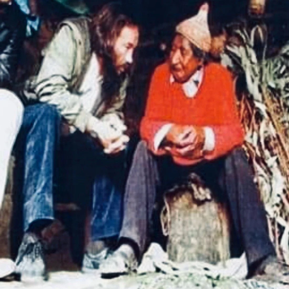 Juan Nuñez Del Prado Behar (wearing a gray jacket and jeans), talking to his mentor Don Benito Qoriwaman (wearing a red sweater, grey pants, and a knitted hat), in his kitchen in Wassau, Peru, circa 1979.