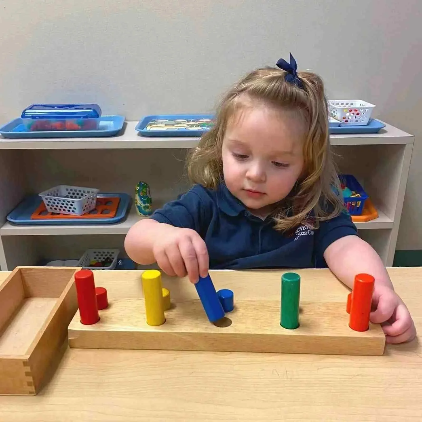 Toddler using a wooden pegboard for fine motor skills development in the classroom, Allen, TX
