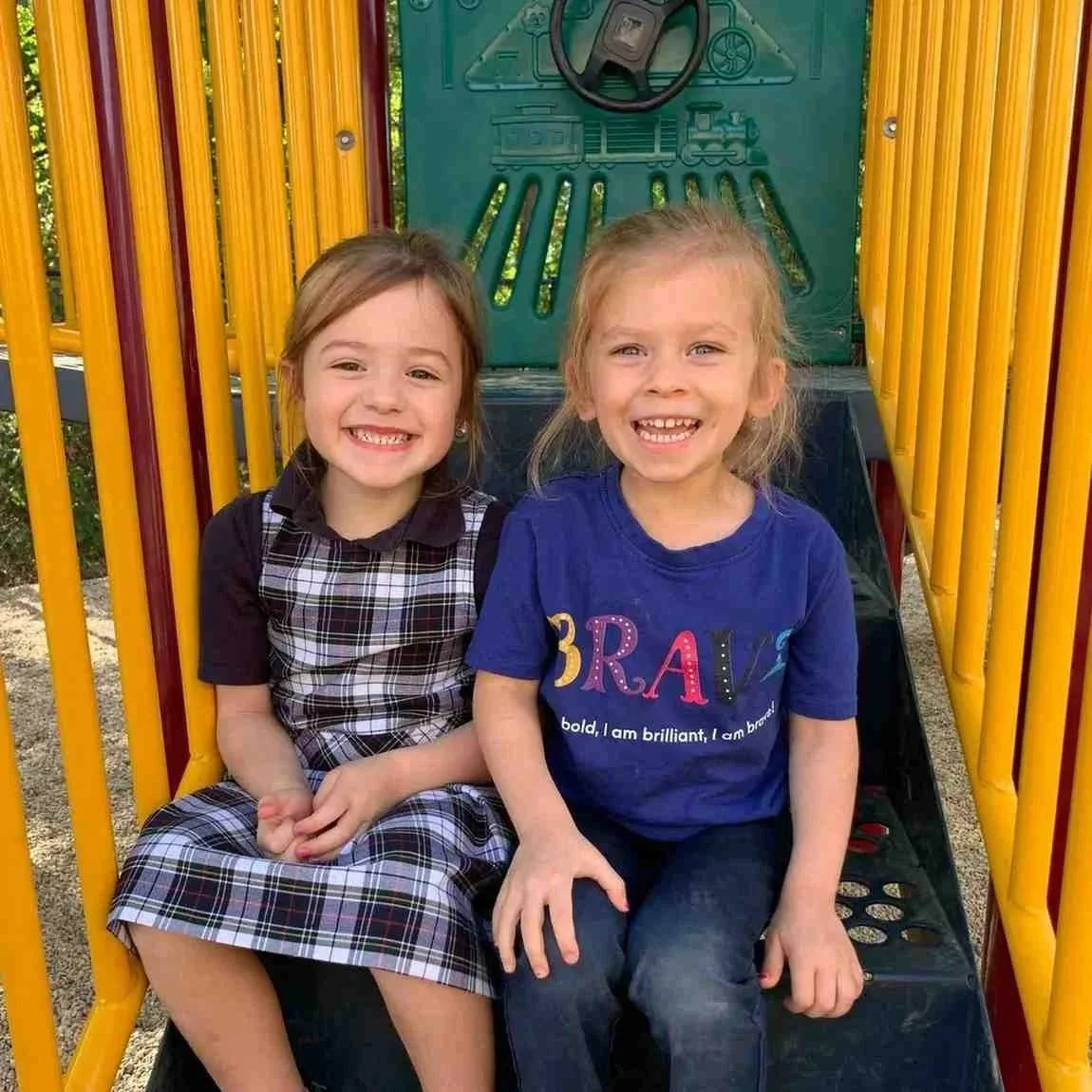 Two Montessori primary girls sitting on a playground slide in Allen, TX
