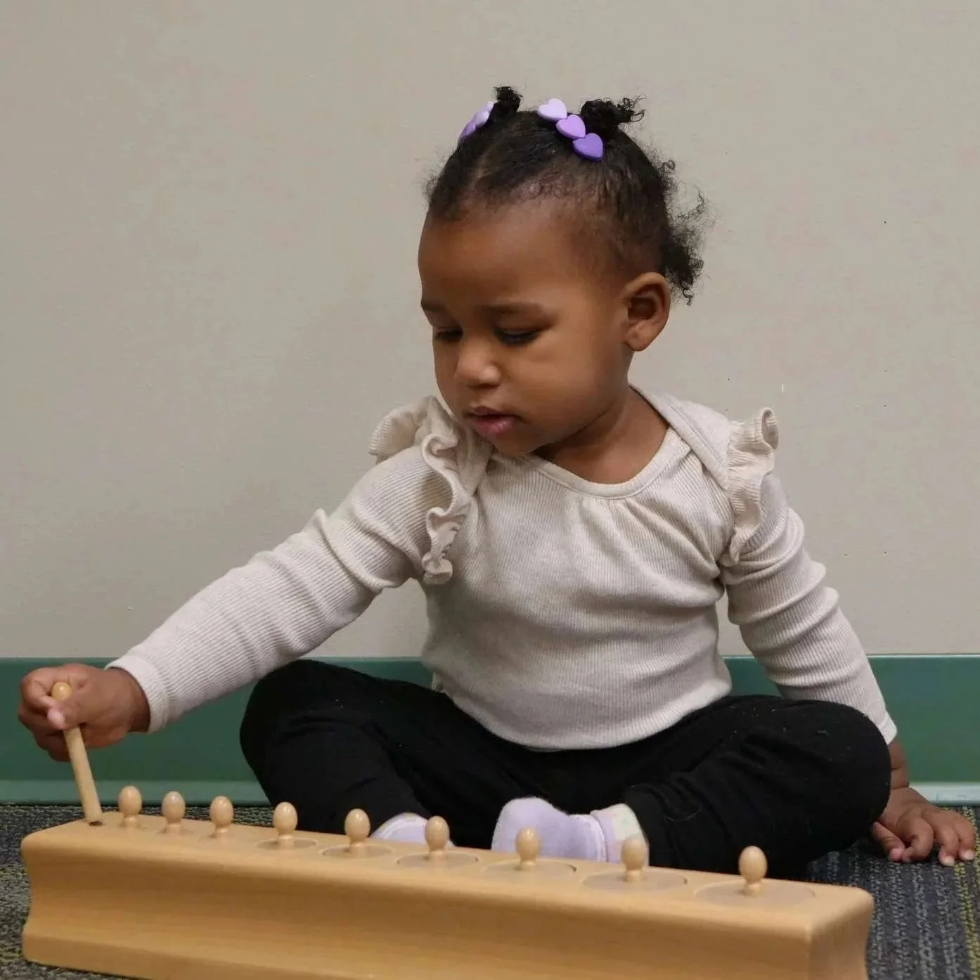 A Montessori infant playing with a wooden toy in Allen, TX
