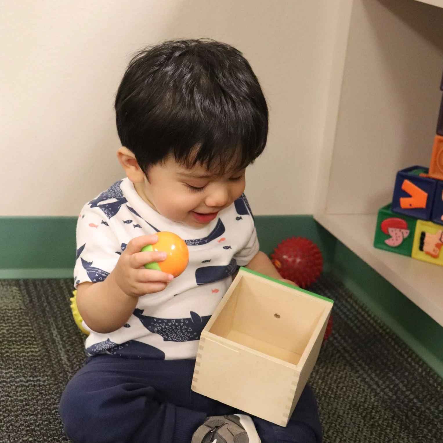 Infant seated on classroom floor exploring Montessori toys in Allen, TX
