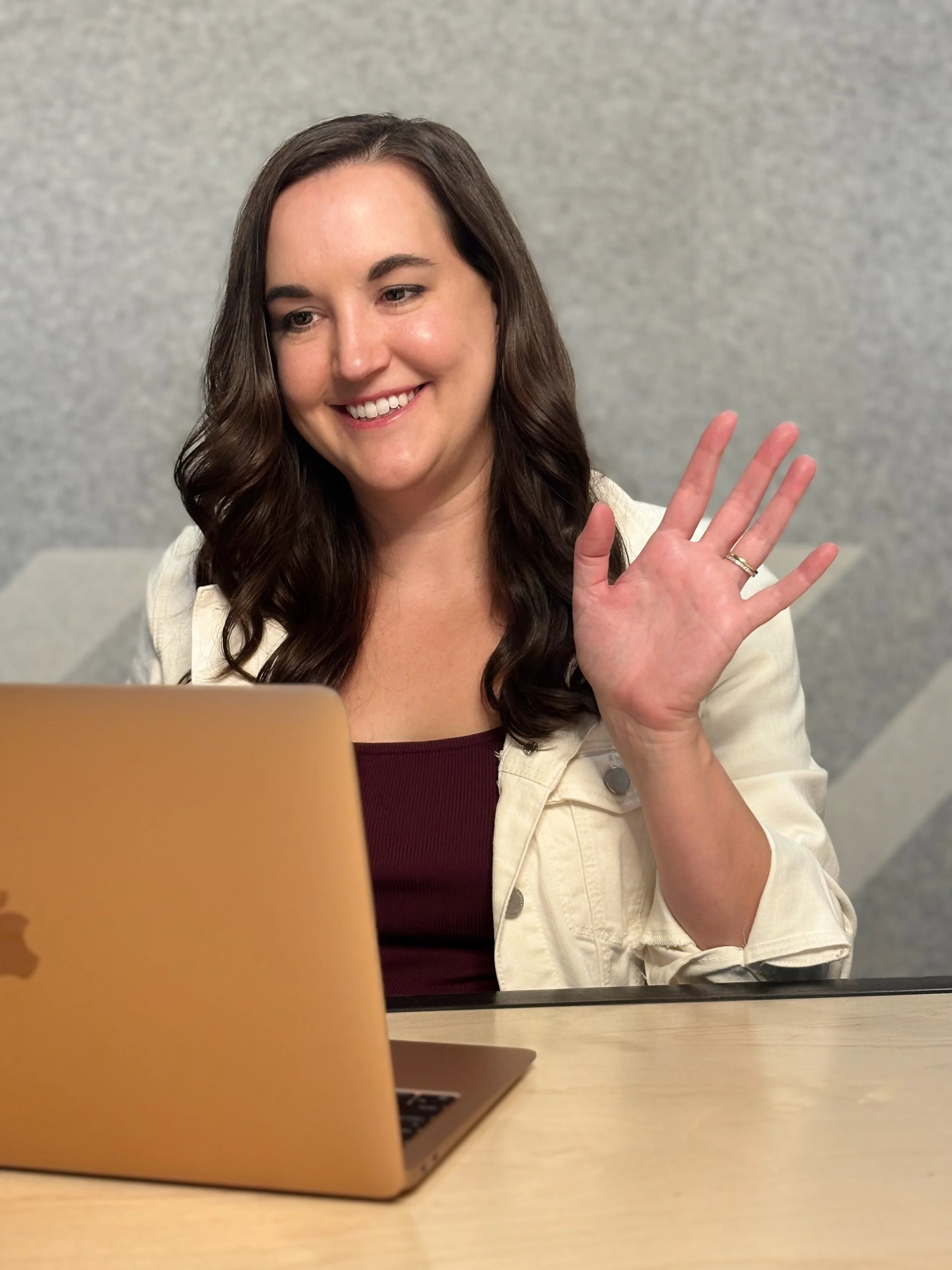 Leadership Coach Brittany Canaski staring at laptop smiling and waving.