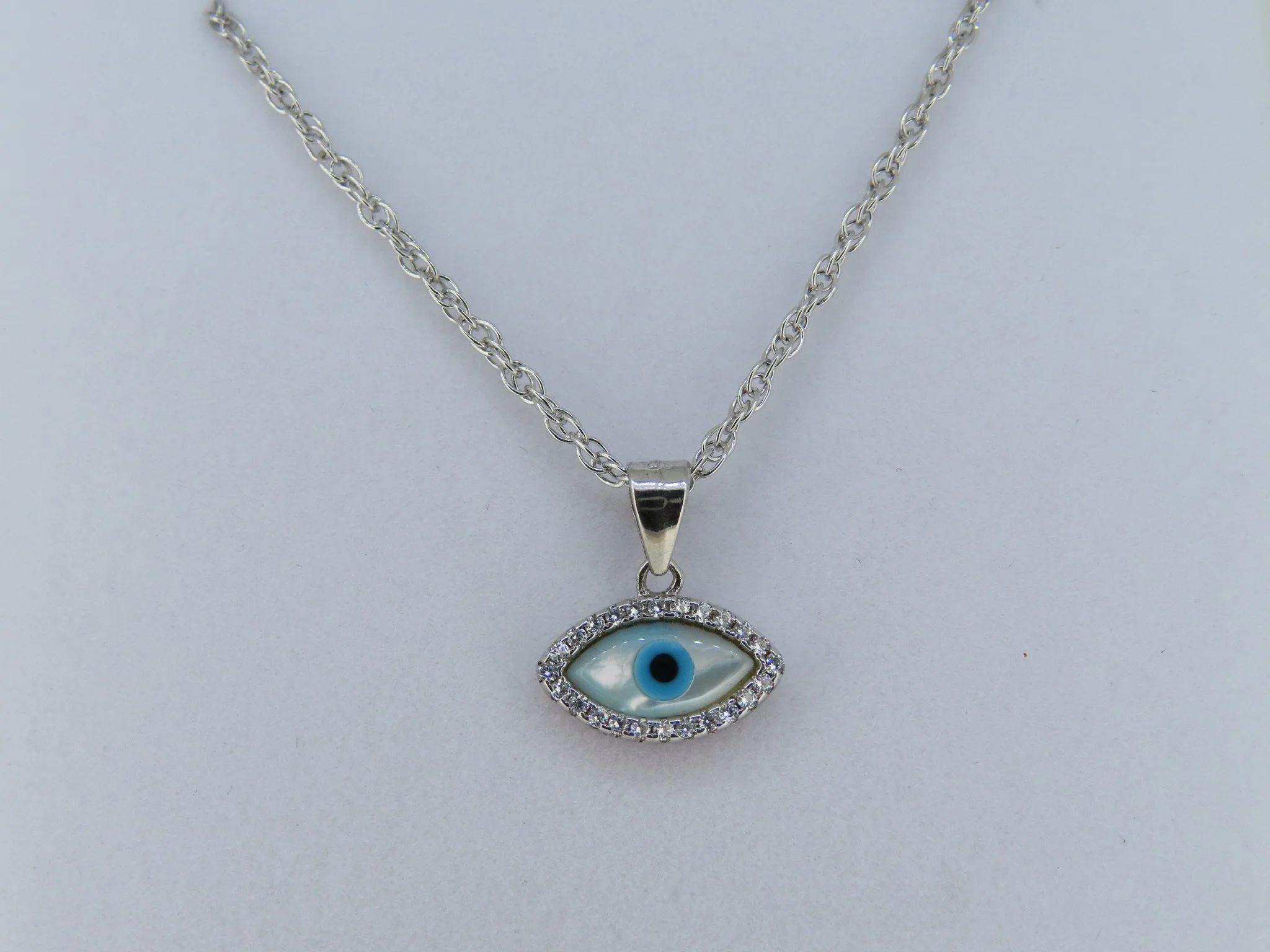 A beautiful blend of elegance and symbolism: Sterling Silver Mother of Pearl Evil Eye Necklace 👁️ 

A modern take on a timeless symbol, this luminous mother-of-pearl pendant features a vivid blue center surrounded by a sparkling pav&eacute; halo of 