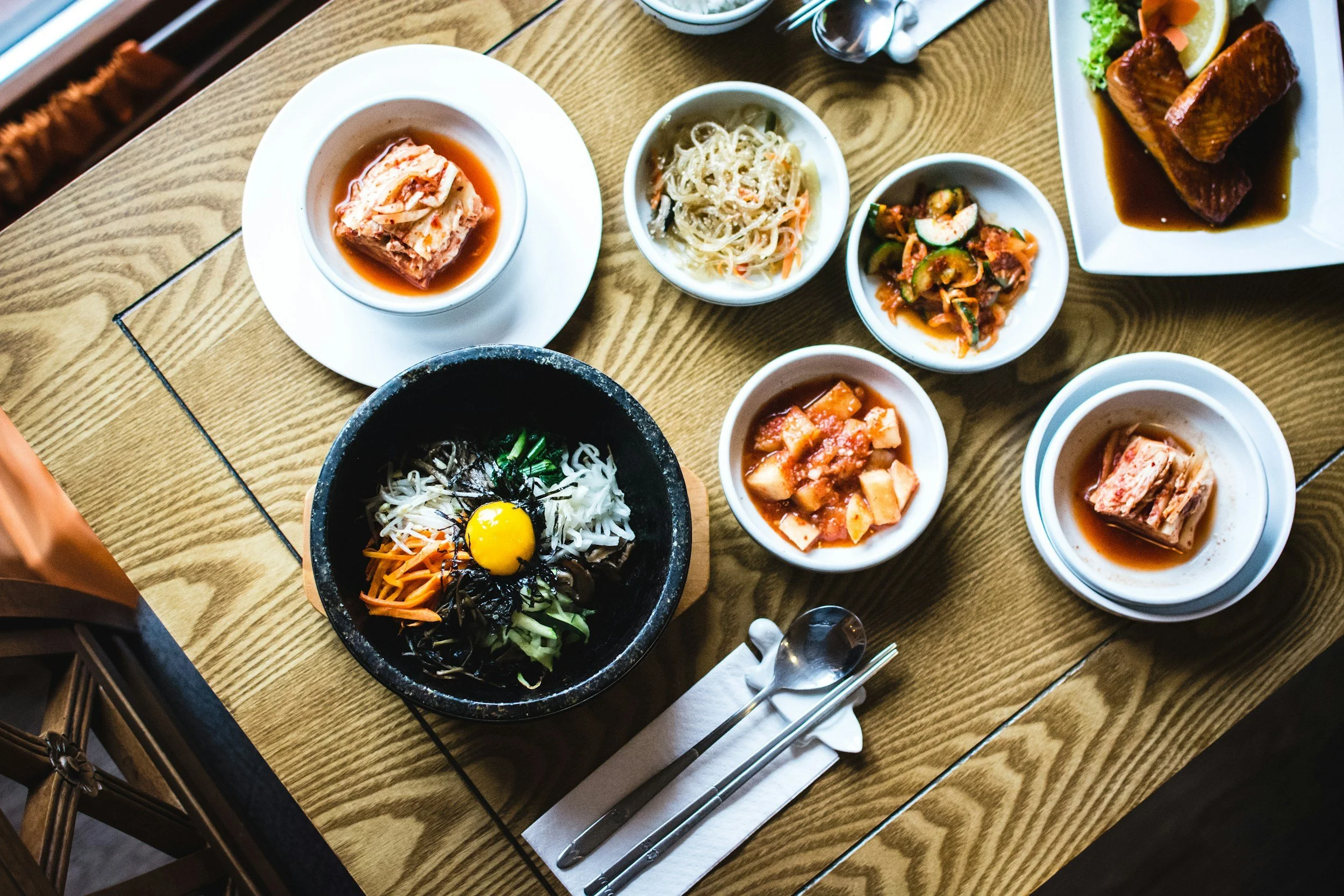A Korean table full of dishes, inclduing kim chi and bibimbap