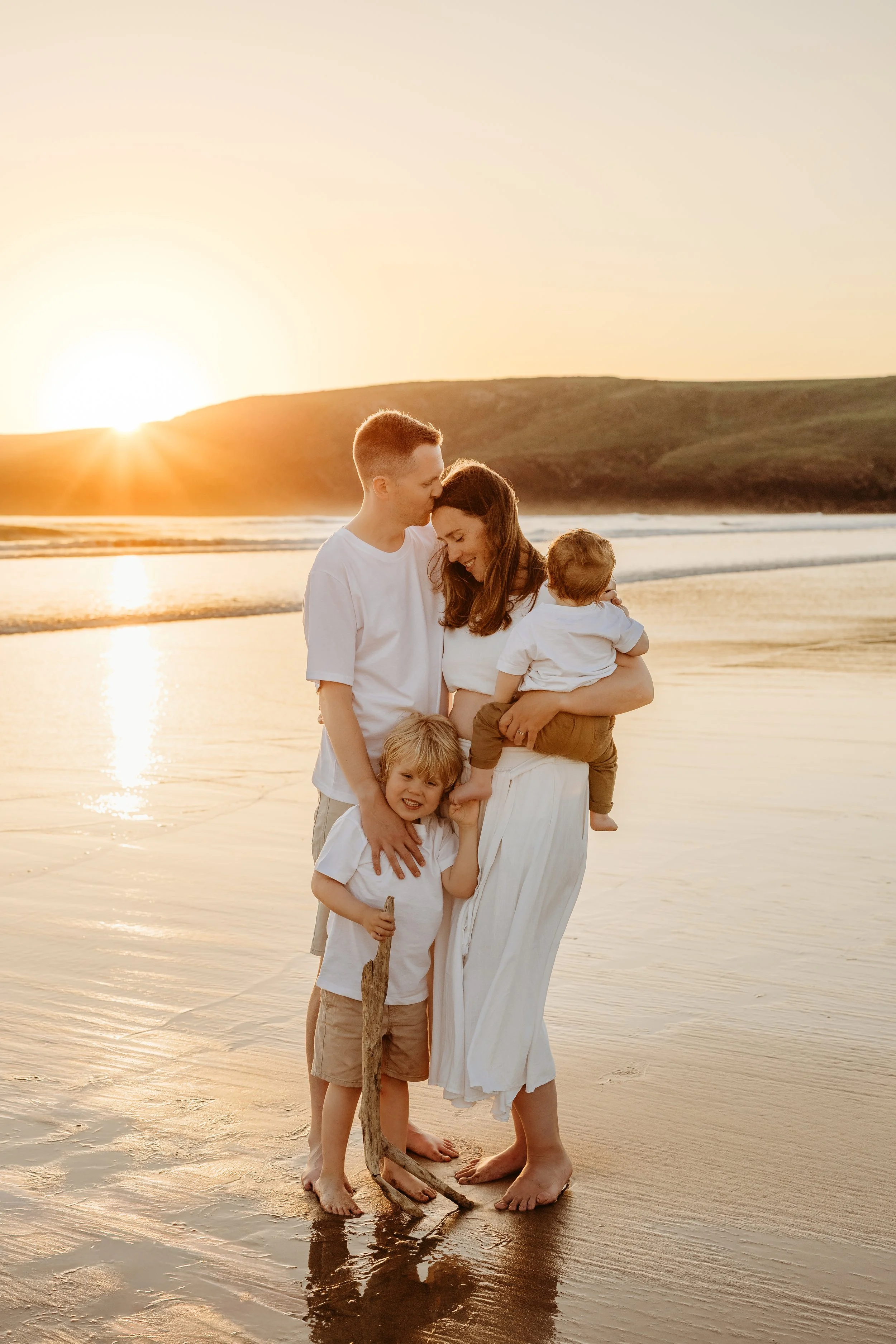Family of 4 having cuddles on the beach at sunset