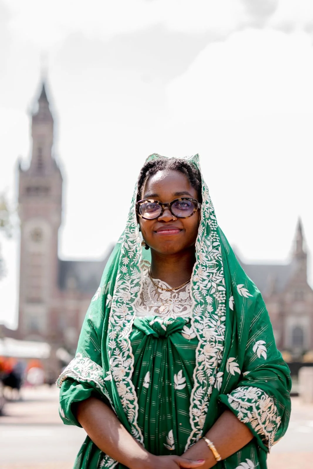 Samira in a light blue blouse with short hair, wearing a necklace and small loop hearrings.