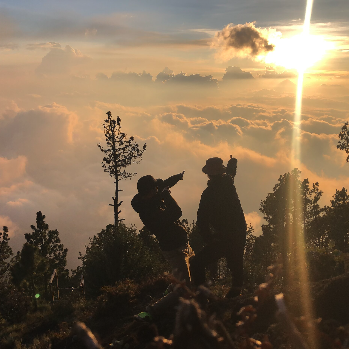 Silhouettes d'une personne jouant de la guitare et d'un cheval au coucher du soleil, avec un ciel nuageux en arrière-plan.