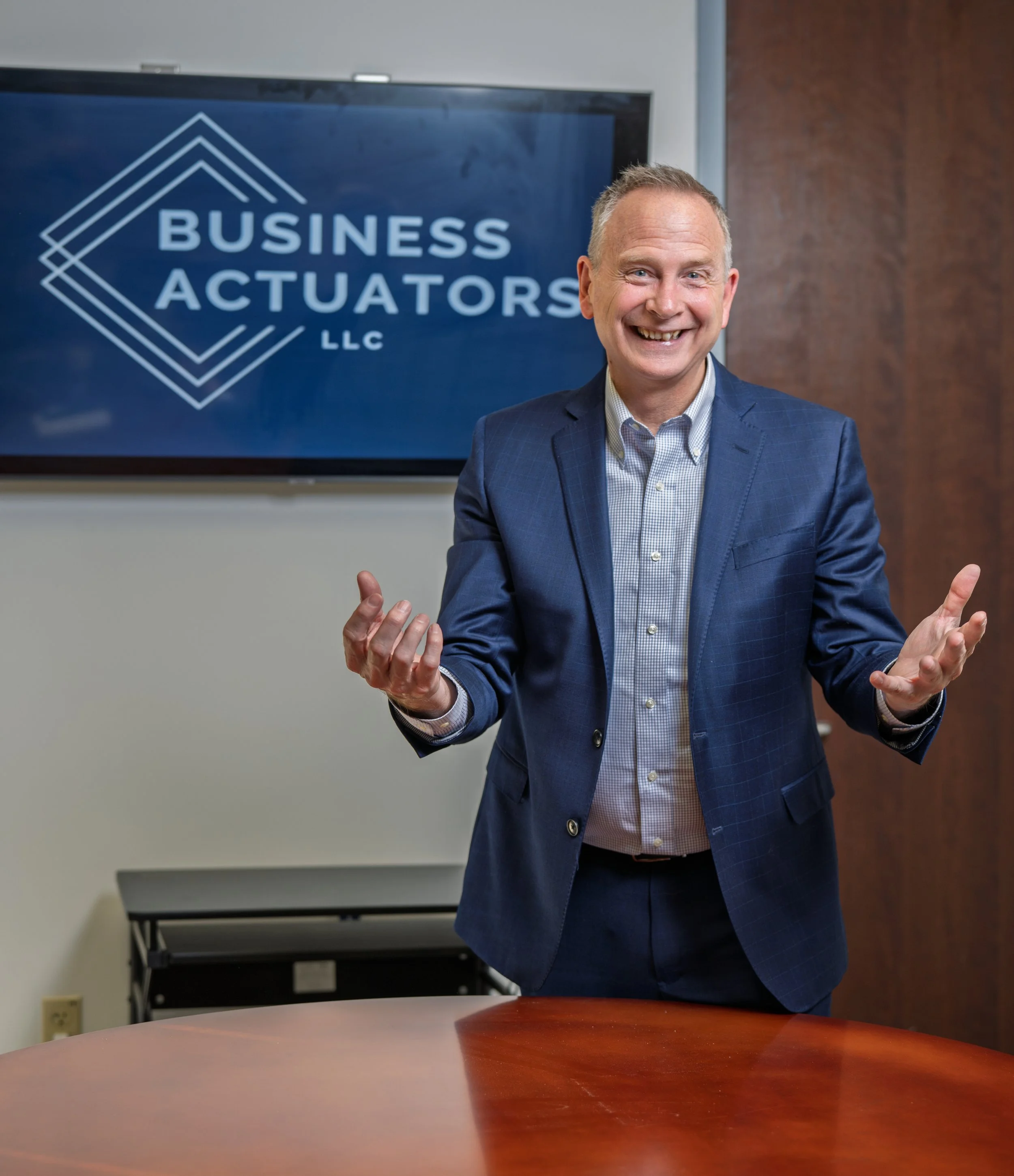 Business leadership speaker presenting practical growth and strategy insights and delivering leadership and business growth keynote presentation  in front of a the logo 'Business Actuators LLC'.