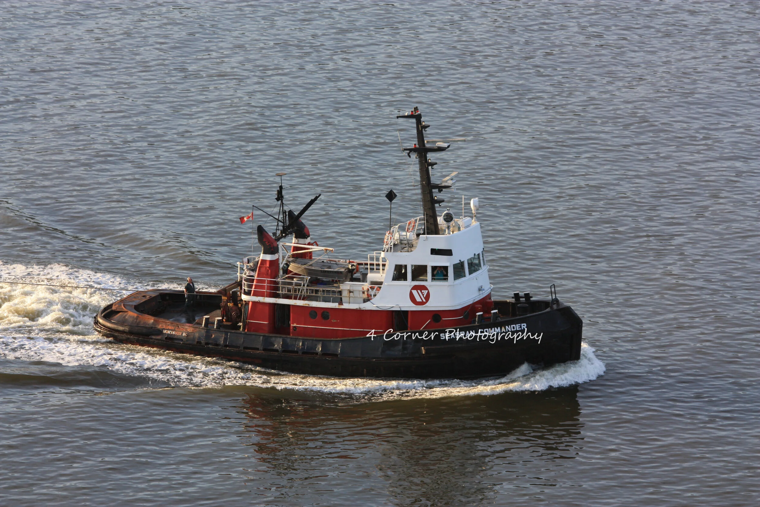 A red and black tugboat named 'SEAFORTH SCOUT' moving through the water, creating wake behind it.