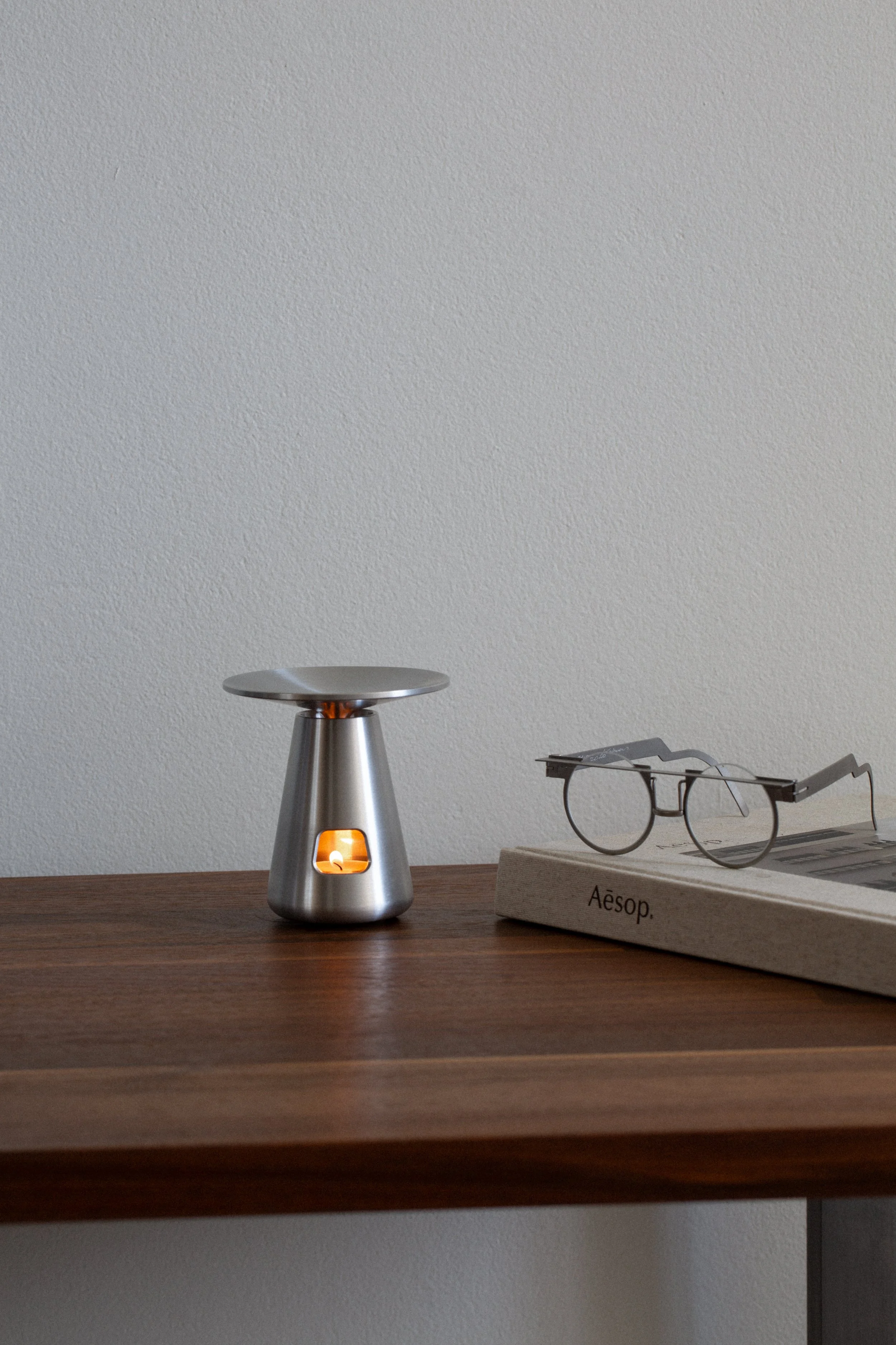Umbo oil burner Aesop in brushed aluminium, a mushroom-inspired essential oil burner and tea light holder for the home. Oil aromatherapy diffuser, front view.
