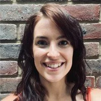 Person smiling in front of a brick wall background.