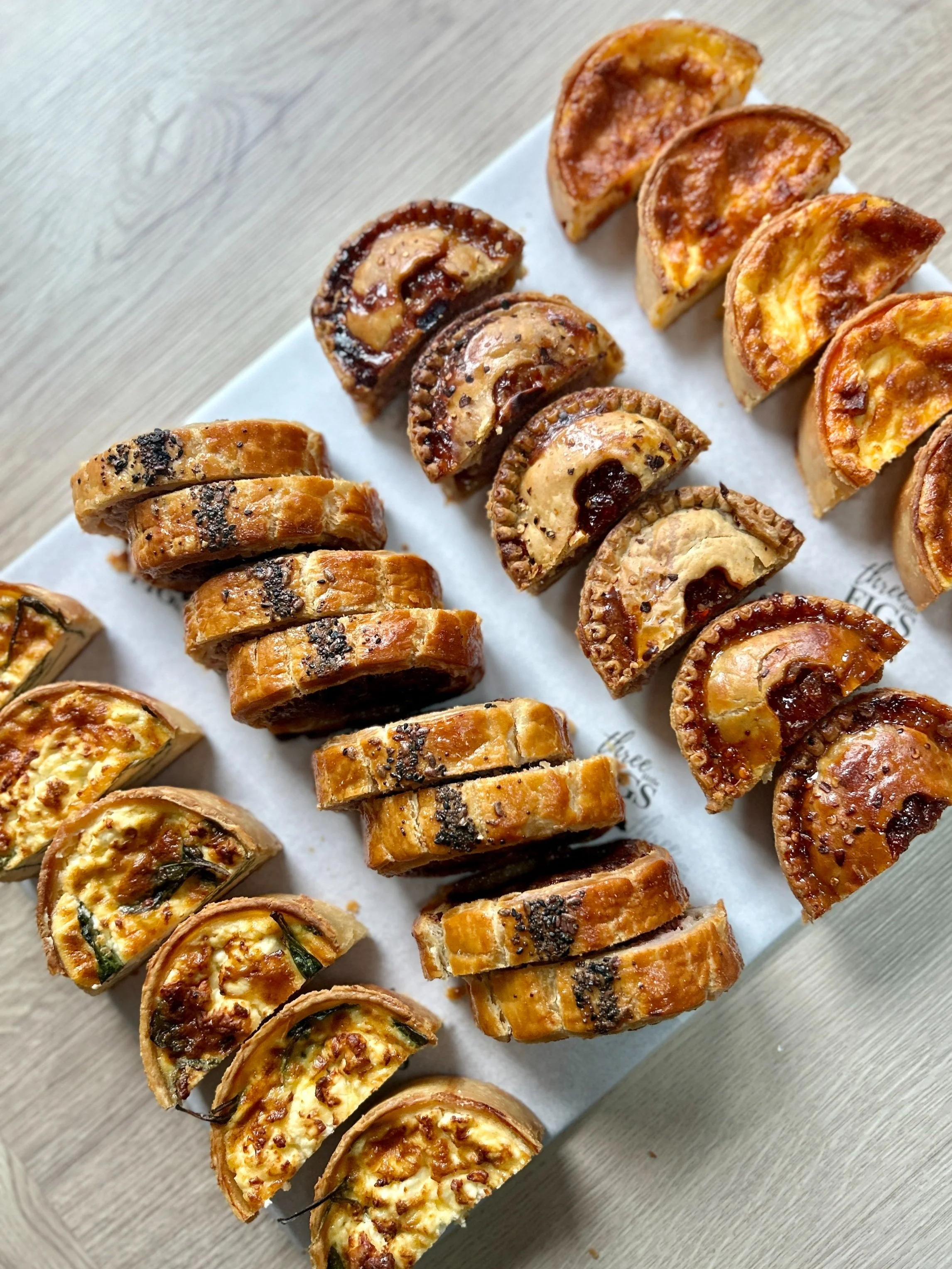Assorted mini quiches and empanadas on a white platter.