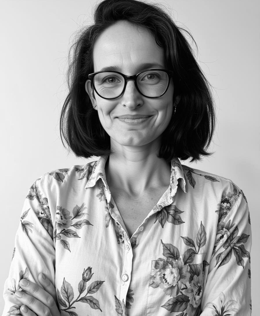 A woman with dark hair, glasses, and a floral shirt smiling at the camera.