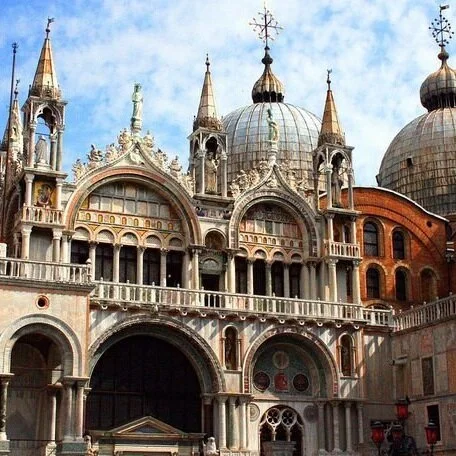 South façade of church, abutting the Doge’s Palace, clad in polychrome marble. Unadorned brickwork is visible on the right in front of the dome.