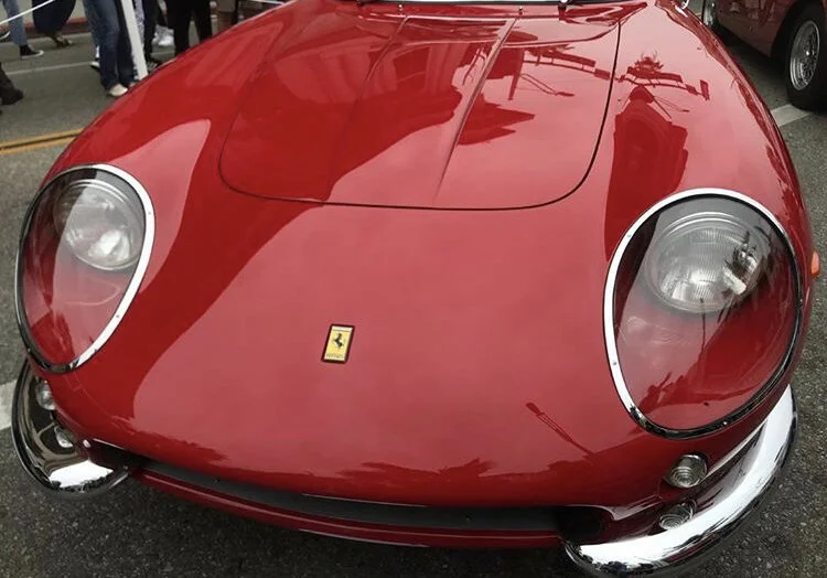 Front view of a red vintage Ferrari sports car with a sleek, curved design and a Ferrari emblem on the hood.