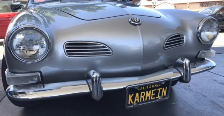 Front view of a vintage silver Toyota car with a California license plate reading 'KARMEIN'