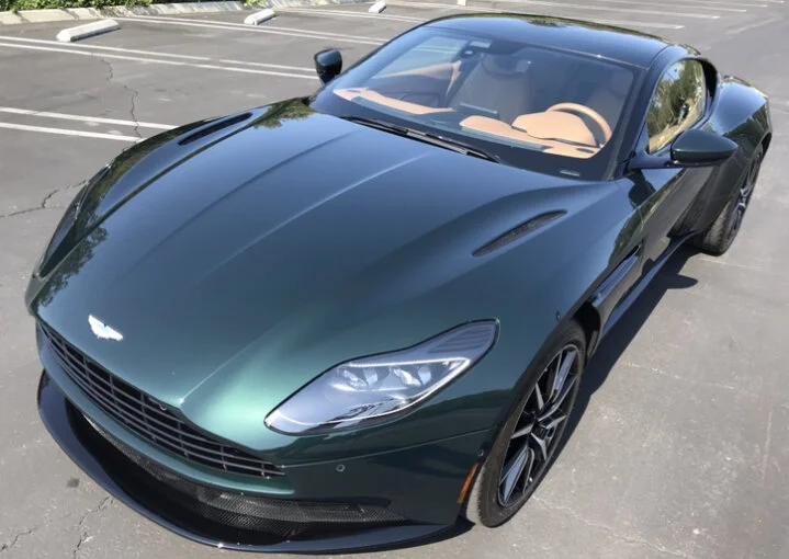Green Aston Martin sports car parked on asphalt.