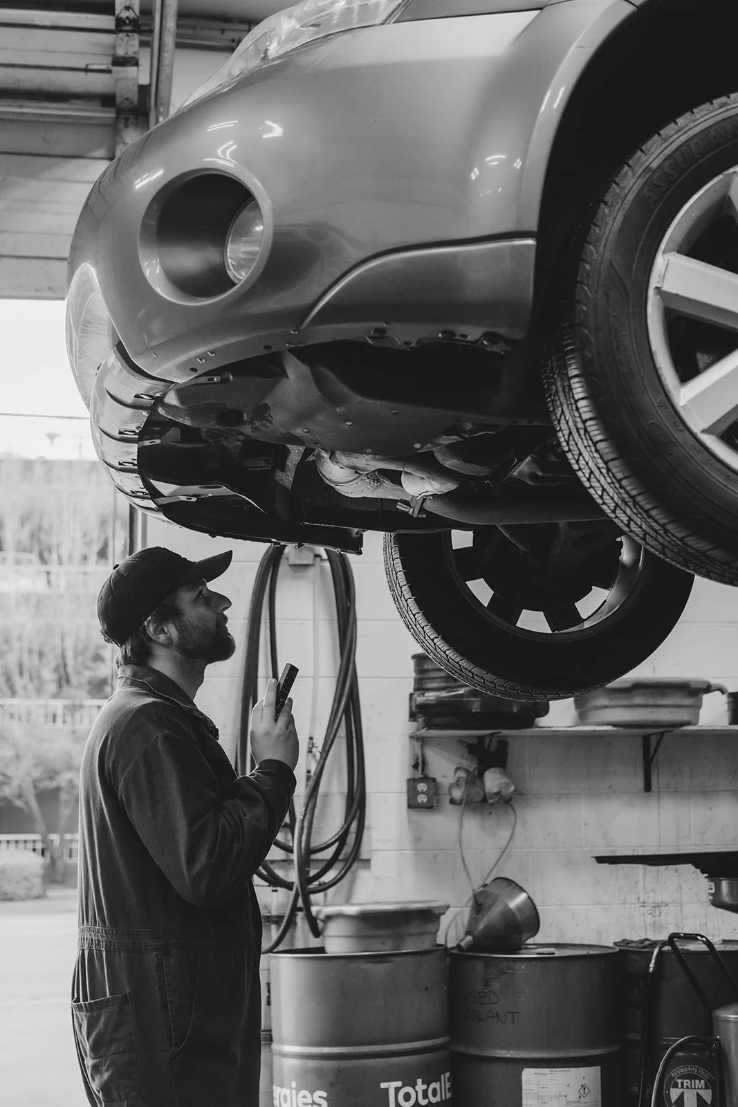 Mechanic with flashlight looks at undercarriage of vehicle