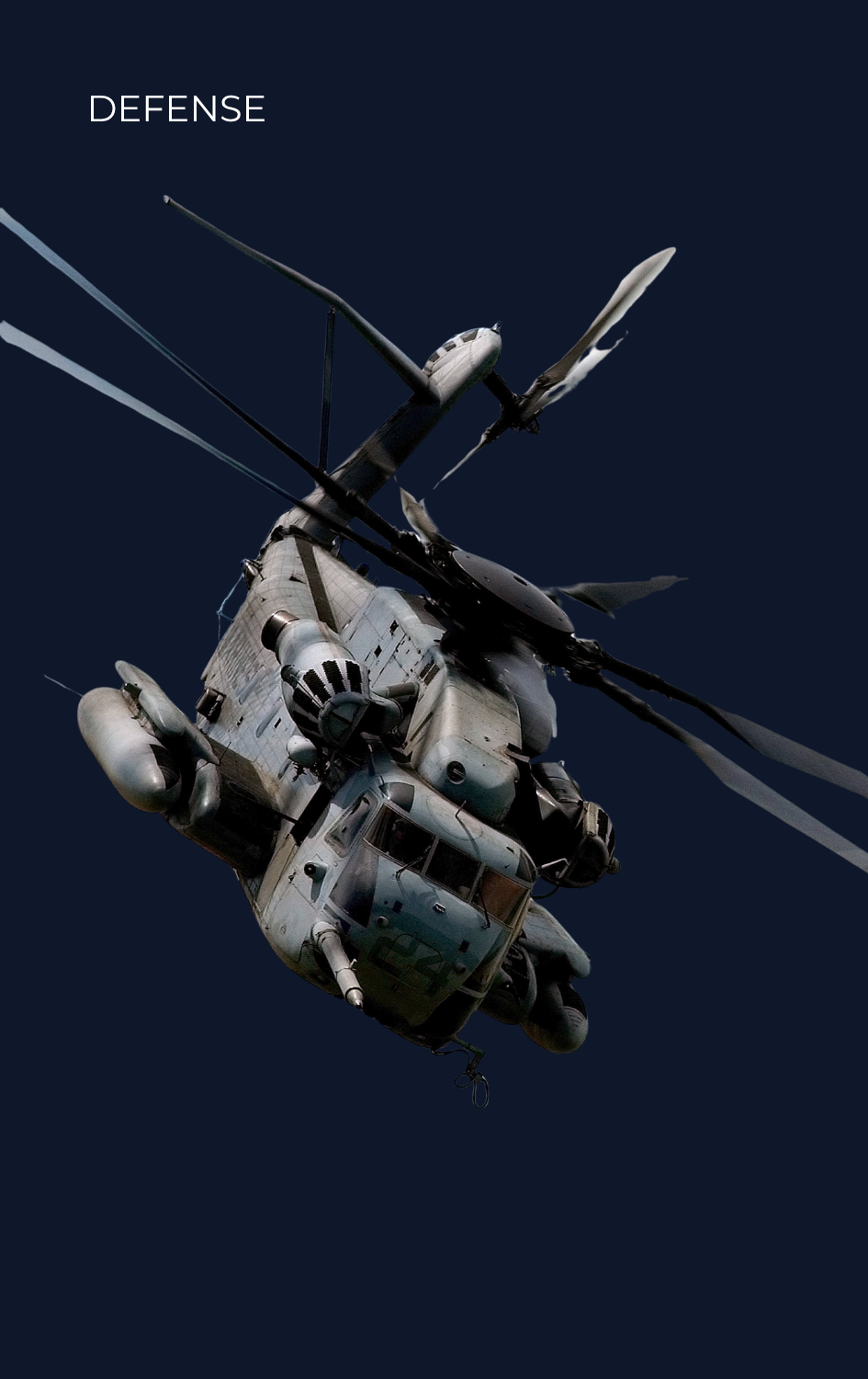 A military helicopter flying against a dark sky with the word 'DEFENSE' written in the upper left corner.