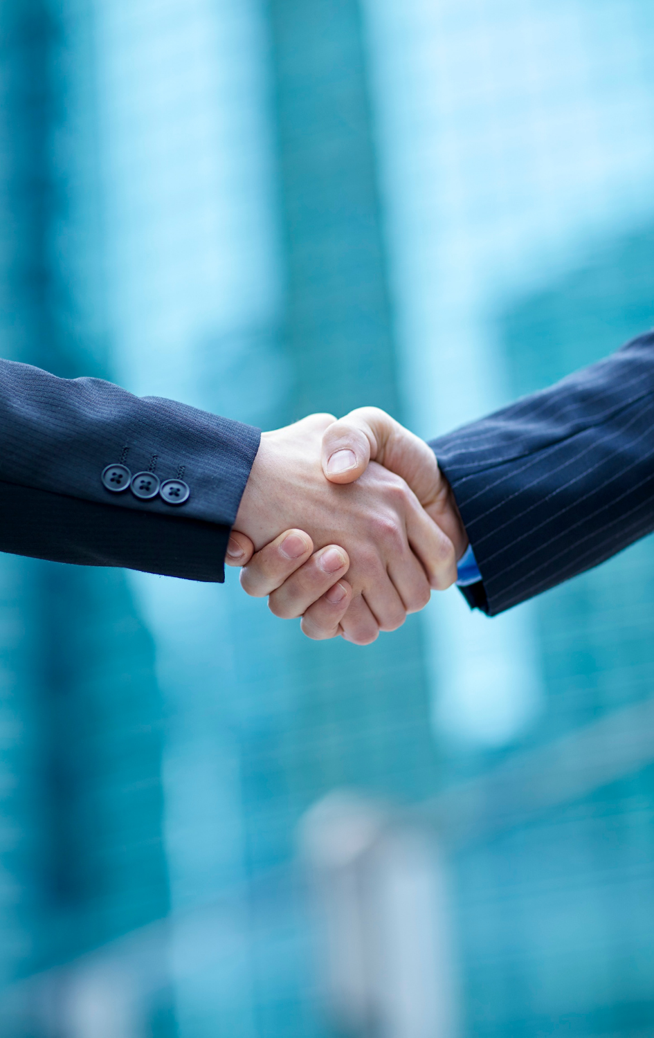 Two people in business suits shaking hands.