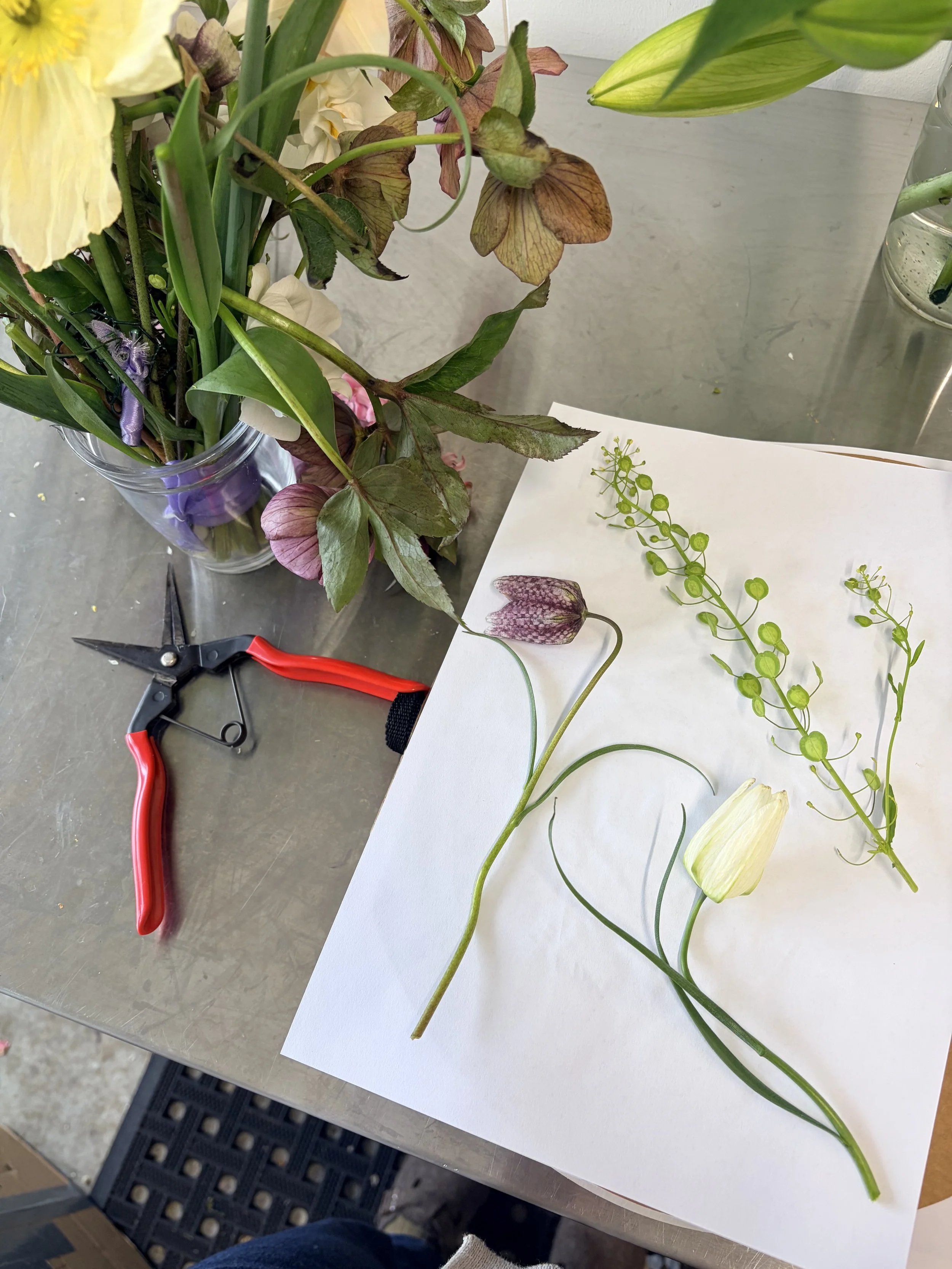Person adjusting a framed floral artwork on a white table.