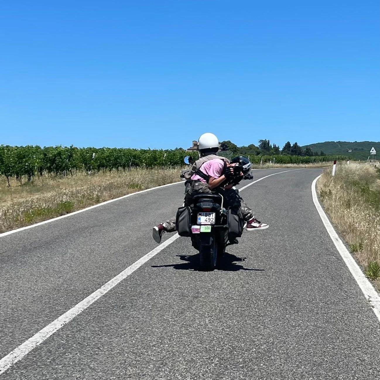 Motorbike ahead on an empty road between vineyards, the view when shooting a cycling race from a moto