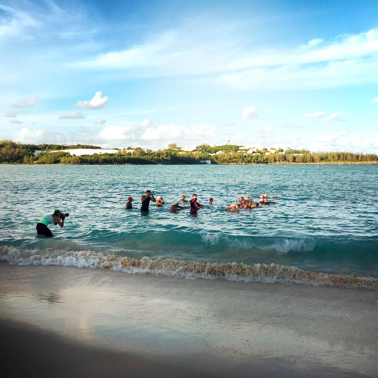 Triathletes in open water at a swim start with a headland behind, Bermuda