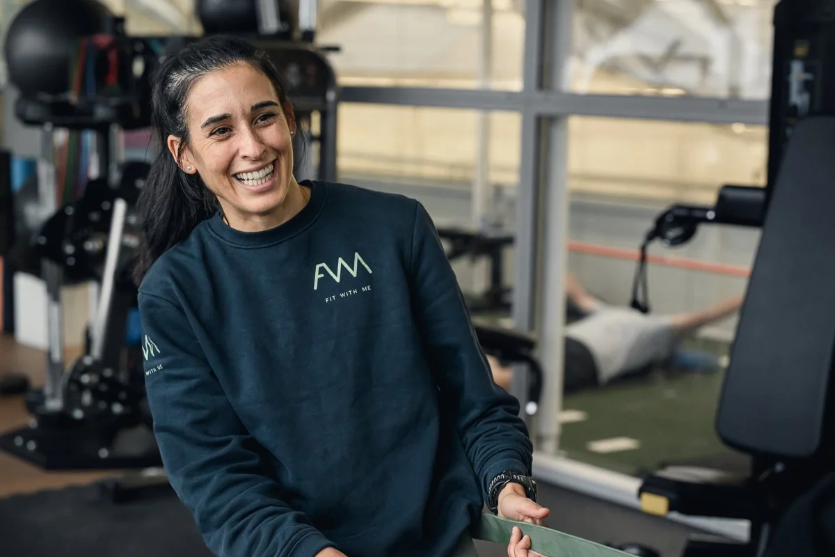 Fit With Me trainer laughing mid session while holding a green resistance band