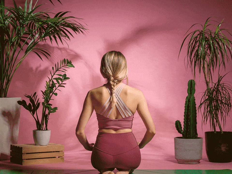 Yoga practitioner in prayer position on a Liforme mat against a pink studio backdrop